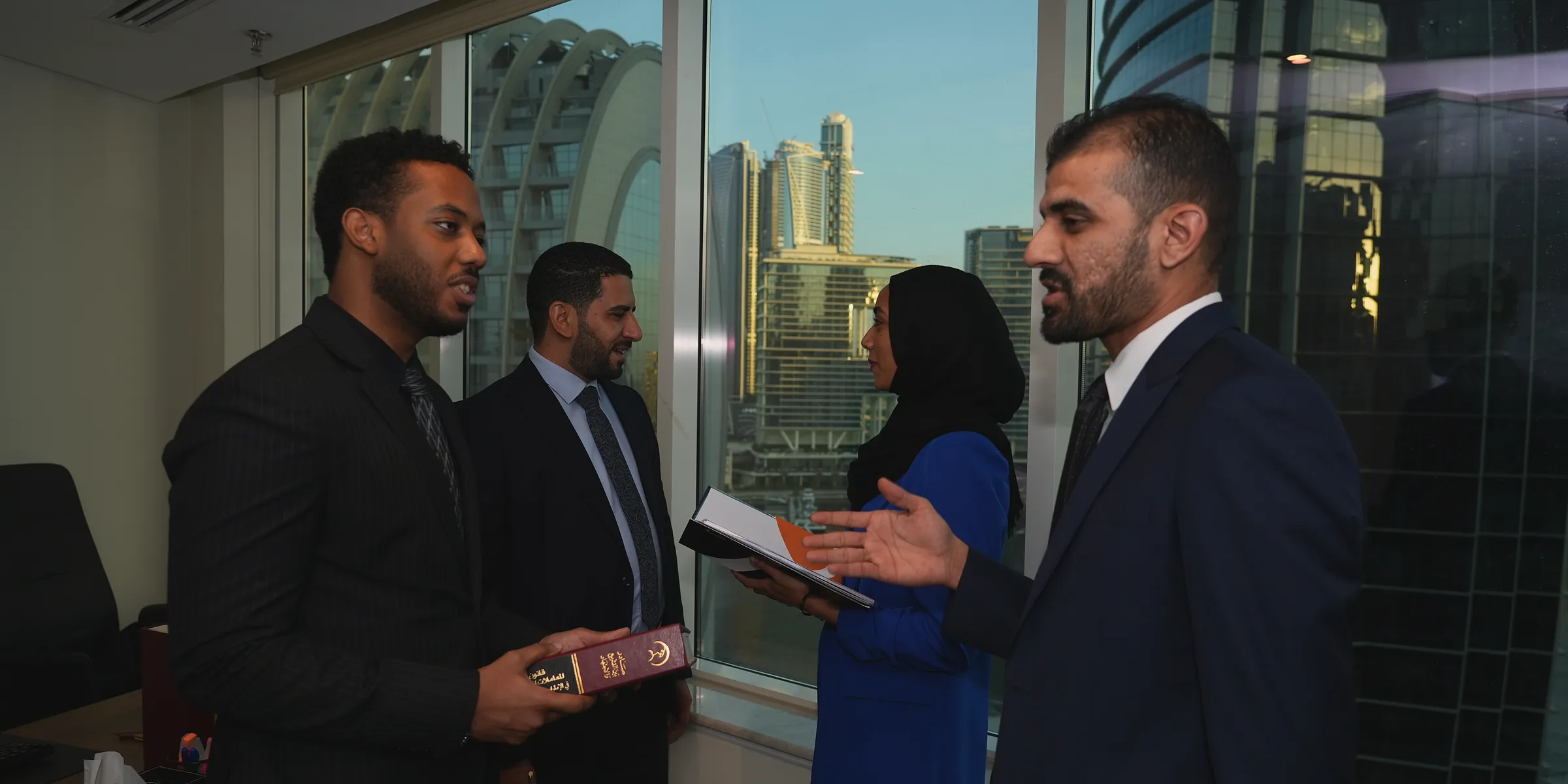 زملاء يتحدثون بجانب نوافذ مكتب تطل على أبراج دبي