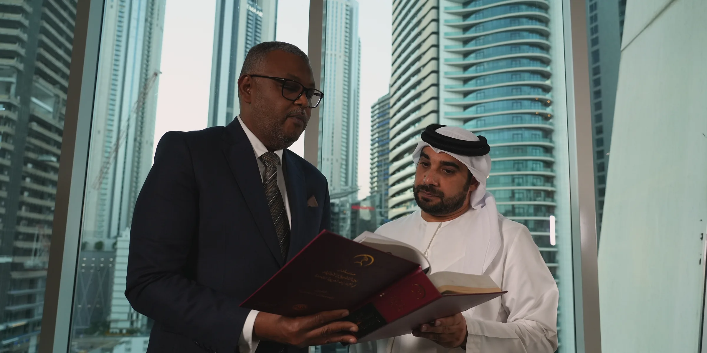 رجلان يقرآن كتاب قانون بجانب نوافذ مكتب