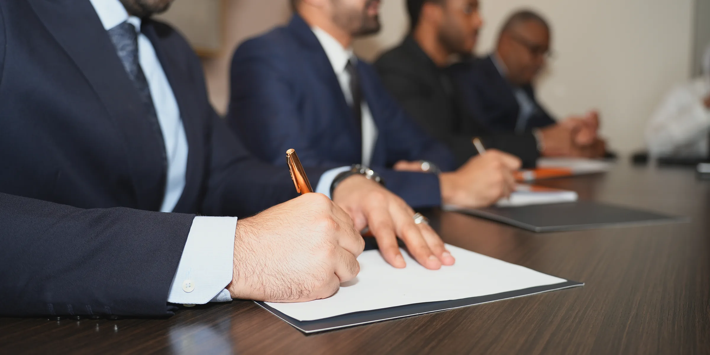 رجل يوقّع مستنداً على طاولة اجتماعات